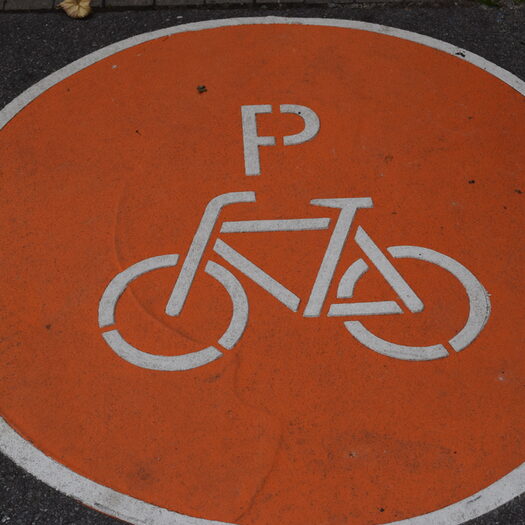 Ein großes Fahrrad-Logo in Orange auf Asphalt