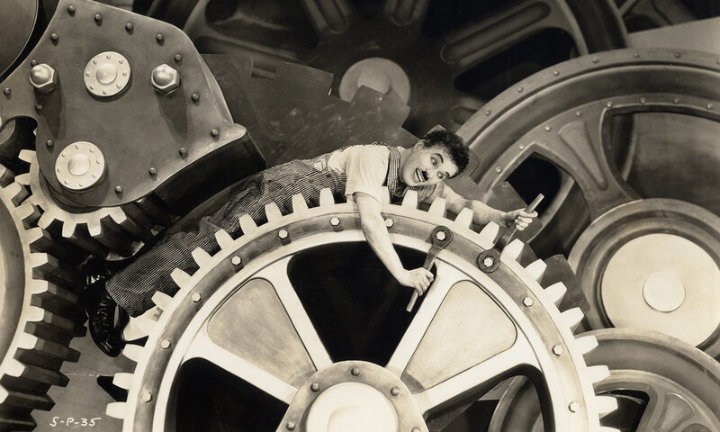 Berühmte Szene aus dem Stummfilm "Modern Times": Charlie Chaplin eingeklemmt zwischen große Zahnräder