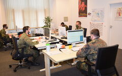 Soldaten in Uniform an Schreibtischen mit Bildschirmen