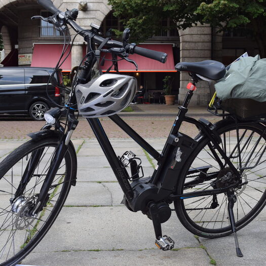 Fahrrad mit Helm und Gepäck steht startbereit auf dem Johannes-Rau-Platz