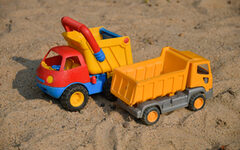 Zwei Spielzeug-Lastwagen in einem Sandkasten
