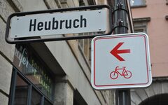 Straßenschild Heubruch mit Ergänzungsschild "Radweg" mit rotem Pfeil und Fahrrad-Symbol