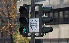 In der Innenstadt weisen Schilder auf die Maskenpflicht hin - hier ein Schild an einer grünen Fußgängerampfel