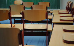 Leere hochgestellte Stühle auf Tischen in einem Klassenzimmer