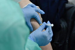 Eine Ärztin spritzt den Impfstof mit einer  Spritze in den Oberarm