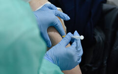 Eine Ärztin spritzt den Impfstof mit einer  Spritze in den Oberarm
