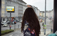Eine Frau steht vor einem Fenster, das auf die Heckinghauser Straße hinausgeht