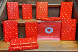 Bücher sind verpackt in rotes Geschenkpapier mit weißen Herzen drauf