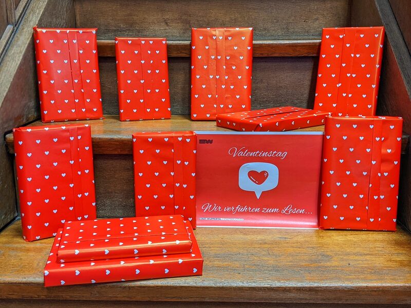 Bücher sind verpackt in rotes Geschenkpapier mit weißen Herzen drauf