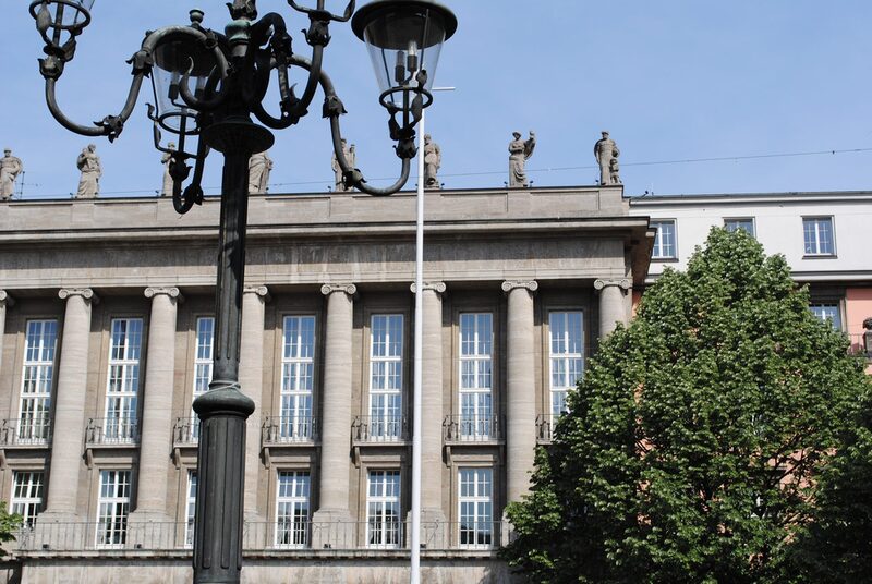 Ausschnitt der Rathausfassade mit historischer Laterne und Baum im Vordergrund