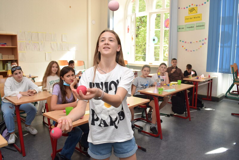 Ein Mädchen jongliert in einem Klassenraum mit Bällen