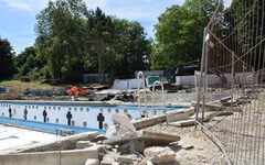 Baustelle im Freibad: Baumaterial und Betonbrocken, im Hintergrund das leere Schwimmbecken