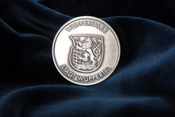 Die Auszeichnung - eine Medaille mit Wuppertaler Stadtwappen - vor blauem Samt