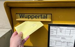 Eine Wahlbrief wird in einen Briefkasten eingeworfen