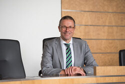 Portrait Oberbürgermeister Uwe Schneidewind mit weißem Hemd und grauem Jacket im Ratssaal