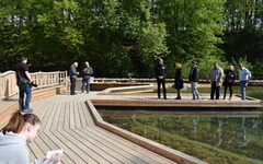 Bei einem Pressetermin stehen Menschen auf Stegen am neuen Teich der Station Natur und Umwelt