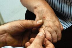 Eine Person hält die Hand einer Seniorin.
