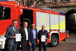 Matthias Nocke, Maik Eckelmann, Uwe Schneidewind, Martin Lehmann vor einem Feuerwehrfahrzeug mit dem Schriftzug Bayer