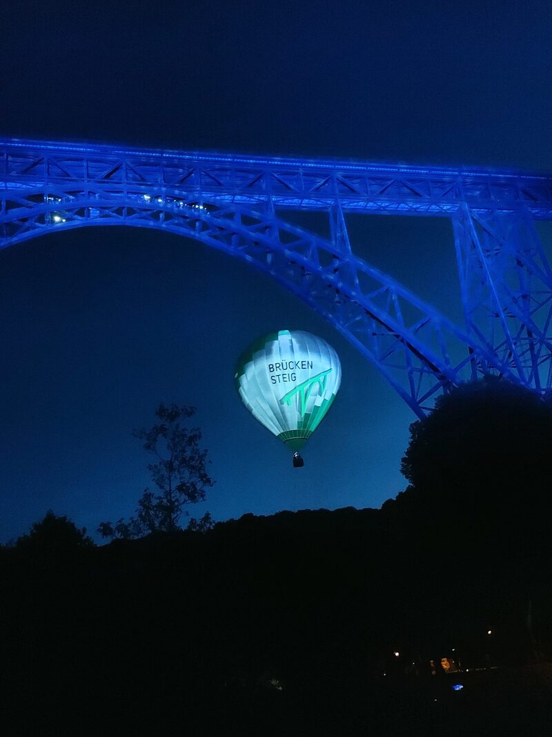 Stahlbrückenträger bei Abendlicht mit leuchtendem Fesselballon