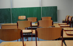 Blick in ein Klassenzimmer mit hochgestellten Stühlen und einer Tafel