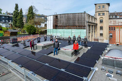 Mitarbeiter des Gebäudemanagements stehen auf dem Dach an der Münzstraße, das mit Photovoltaik-Elementen gedeckt ist.