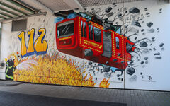 Das Graffiti zeigt einen Schwebebahnwagon im-Feuerwehr-Stil.