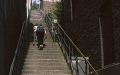 Personen auf einer Treppe zwischen Häusern mit Ziegelmauern.