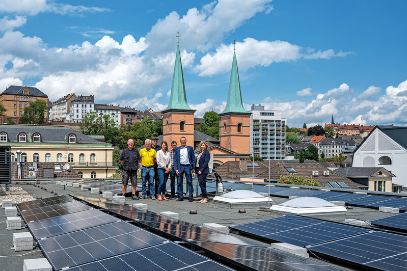 Oberbürgermeister Uwe Schneidewind, Mirja Montag, Leiterin des städtischen Gebäudemanagements, und Mitarbeiter auf dem Dach der Bergischen Volkshochschule. Es ist mit Photovoltaik-Elementen ausgestattet.