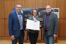 Oberbürgermeister Uwe Schneidewind, Ministerin Ina Scharrenbach und ein Vertreter des Fördervereins Historische Parkanlagen halten den Förderbescheid in der Hand.