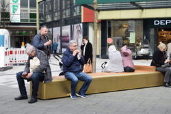 Menschen sitzen auf den neuen geschwungenen Bänken auf dem Von der Heydt-Platz in der Elberfelder City