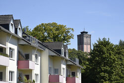 Häuserfassaden im Vordergrund, dahinter ein Wasserturm