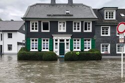 Bergisches Schieferhaus mit grünen Fensterläden ist vom Hochwasser eingeschlossen