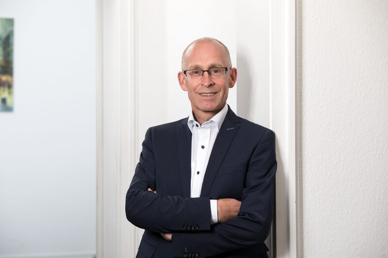 Portrait Stadtdirektor Dr. Stefan Kühn in dunklem Anzug vor weißer Wand
