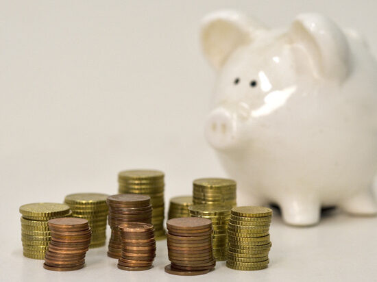 Das Bild zeigt ein Sparschwein und gestapelte Münzen