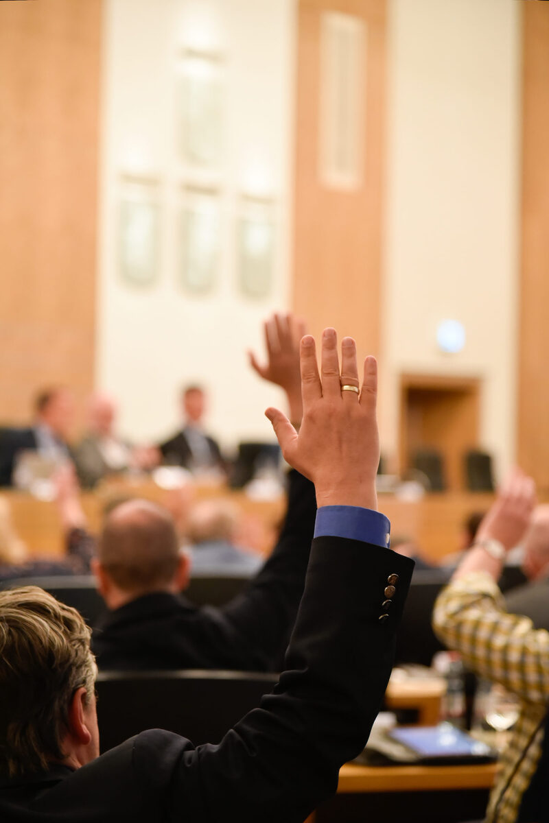 Ein Ratsmitglied hebt die Hand zur Abstimmung bei einer Ratssitzung im Ratssaal Barmen.
