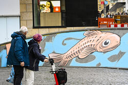 Passanten besehen sich das neue Wandgemälde mit Fisch