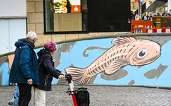 Passanten besehen sich das neue Wandgemälde mit Fisch