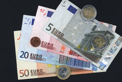 Geldscheine und Münzen auf schwarzem Hintergrund