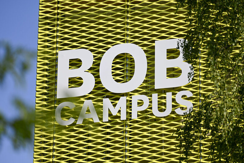 Die Fassade des BOB-Campus hinter grünen Ästen