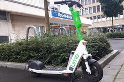 Ein E-Scooter ist an einer grünen Insel geparkt