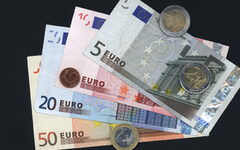 Euro-Geldscheine und -Münzen vor schwarzem Hintergrund