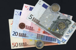 Euro-Geldscheine und -Münzen vor schwarzem Hintergrund