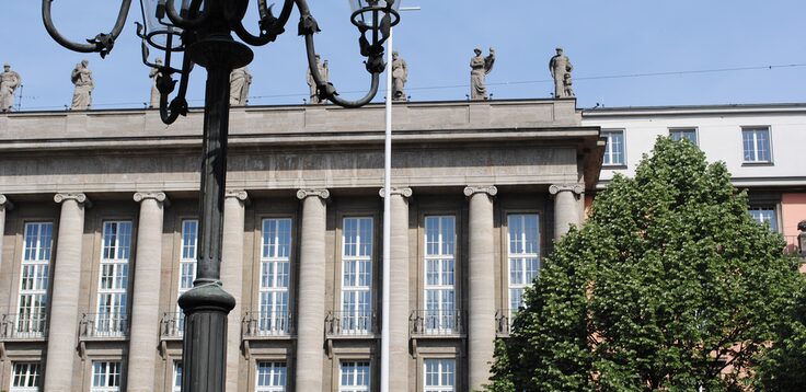 Rathaus-Fassade mit Kandelaber und Baum im Vordergrund
