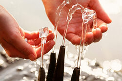 Zwei Hände unter Brunnen-Wasserfontänen