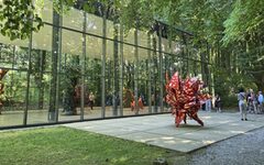 Das Bild zeigt eine Skulptur von Tony Cragg vor der gläsernen Ausstellungshalle gegenüber der Villa Waldfrieden