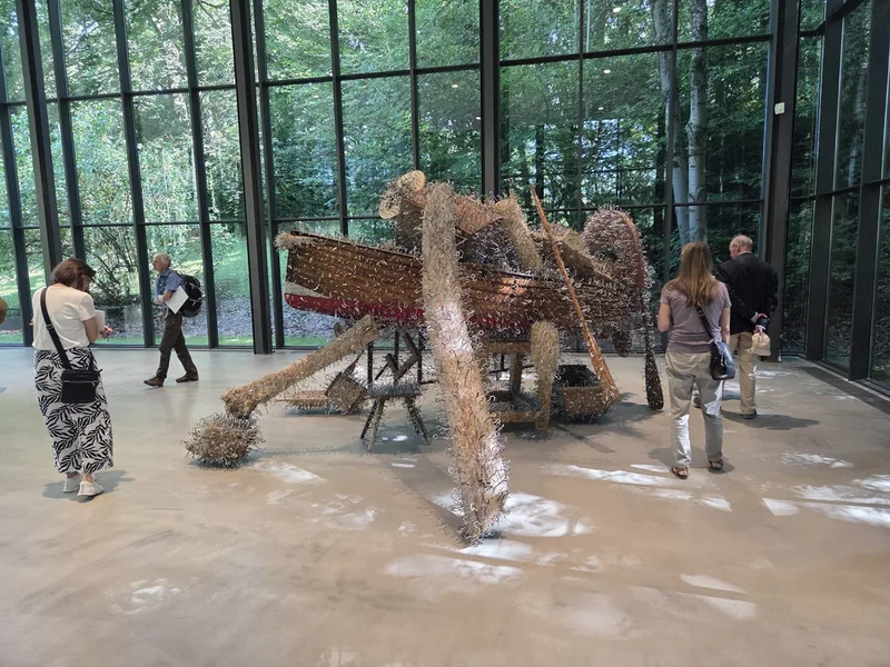 Ein Schiff aus Holz, das komplett mit Metallhaken bedeckt ist, steht in der mittleren Ausstellungshalle