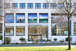 Moderne Gebäudefassade mit Spiegelfenstern und Schriftzug "Haus der Integration"