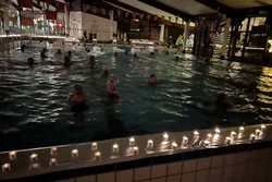 Lichterschwimmen im Gartenhallenbad Langerfeld. Um das Becken stehen zahlreiche Teelichter.
