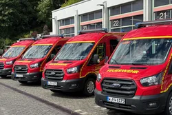 Feuerwehrfahrzeuge in Reihe aufgestellt, im Hintergrund Gebäudefassade mit Glasfronten