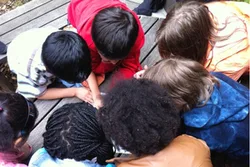 Kinder von hinten, die sich im Kreis über etwas beugen